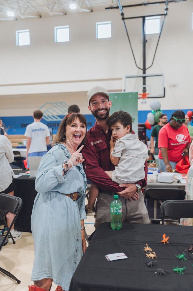 Jacob Richardson and his son greeting a guest at the BNI and Boys and Girls Clubs Trades Expo at the Highland Park Boys and Girls Club